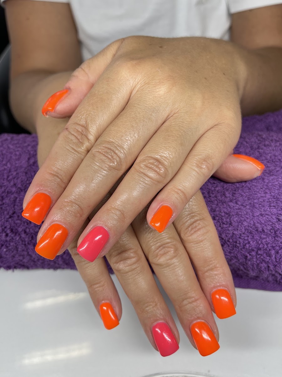 Orange-pinke Gel-Maniküre auf lila Handtuch